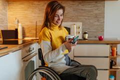 jeune femme en fauteuil roulant dans sa cuisine