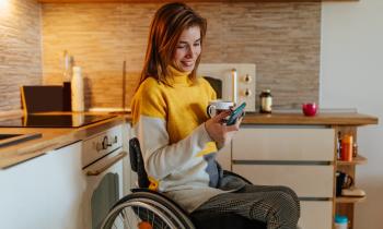 jeune femme en fauteuil roulant dans sa cuisine