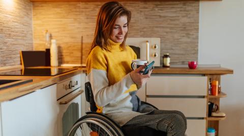 jeune femme en fauteuil roulant dans sa cuisine