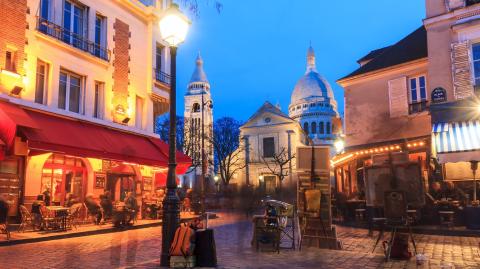 Vue de la place du Tertre de nuit, lieu emblématique du quartier Montmartre, à Paris.