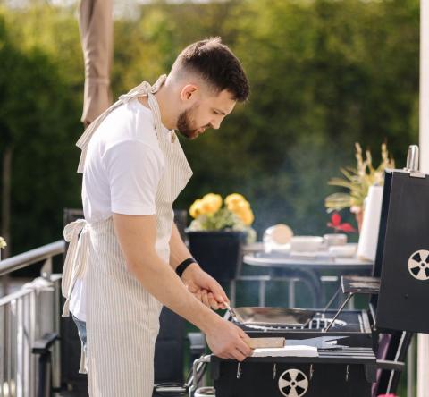 Homme en train d'installer un barbecue sur son balcon
