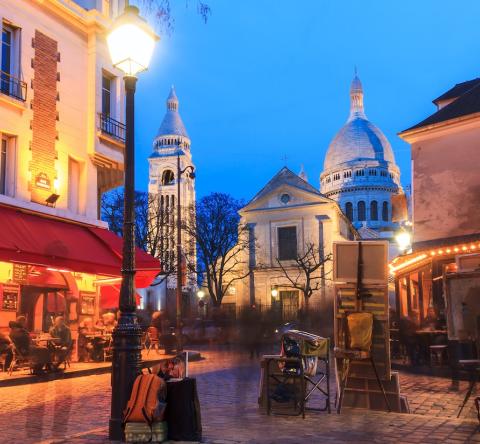 Vue de la place du Tertre de nuit, lieu emblématique du quartier Montmartre, à Paris.